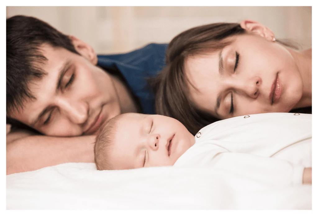 parents sleeping soundly with young baby in front of them. Obviously staged given the mum's perfect make-up!