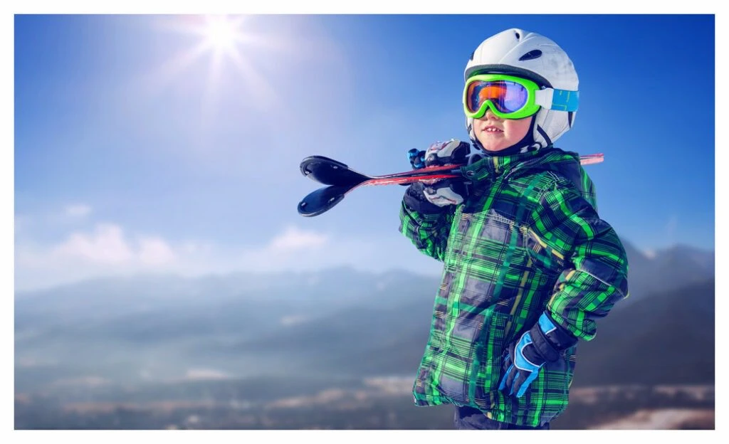 Young boy standing in full brand new ski kit surveying the mountains behind him! 
