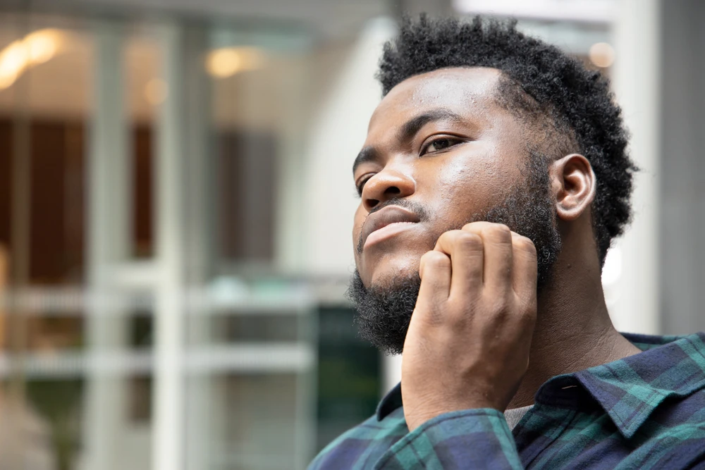 Afro-Caribbean man scratching the eczema on his face